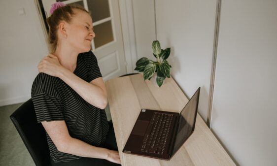 Kvinde med hold i nakken der sidder ved en computer