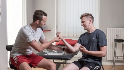 fysioterapeut der behandler person med ondt i hånden med sportsfysioterapi